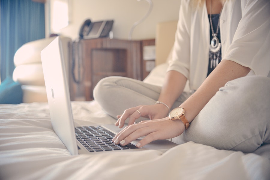 young woman on laptop sitting on bed