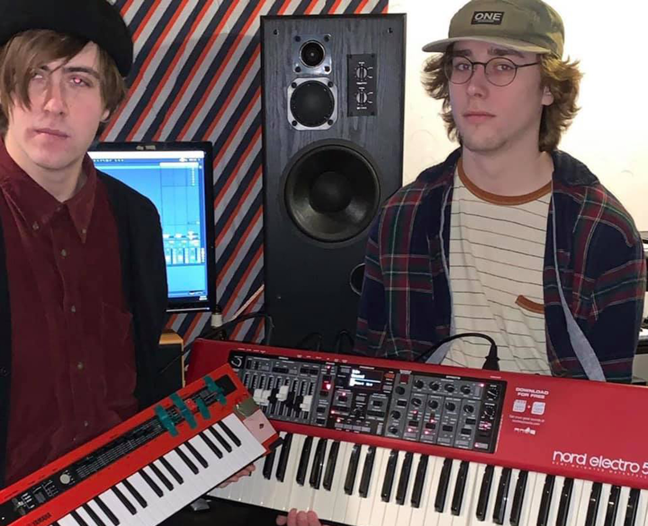 Two bandmates post holding keyboards.