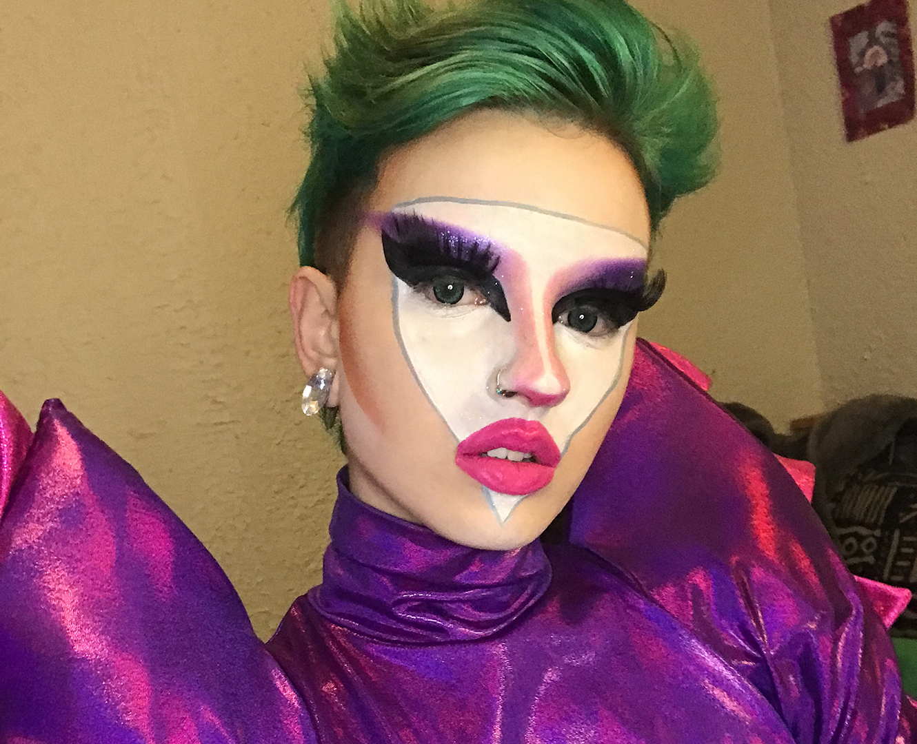 Drag queen poses with green hair and large purple dress