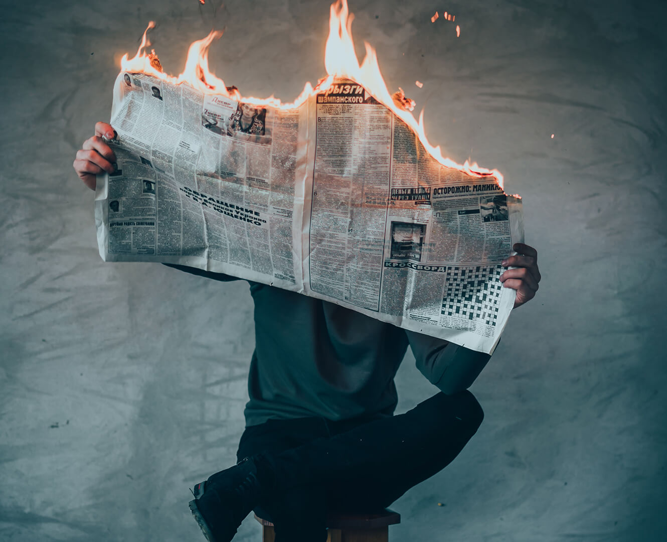 man holding newspaper burning up in flames