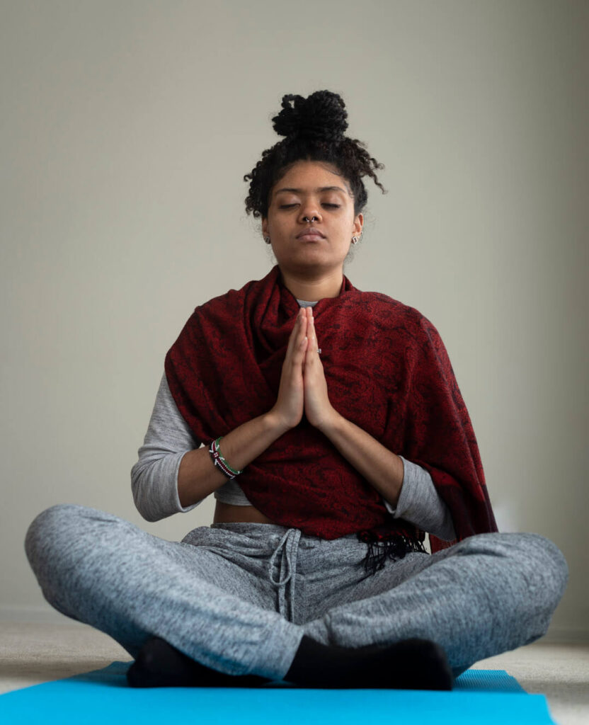 Image of woman sitting cross legged with palms together meditating