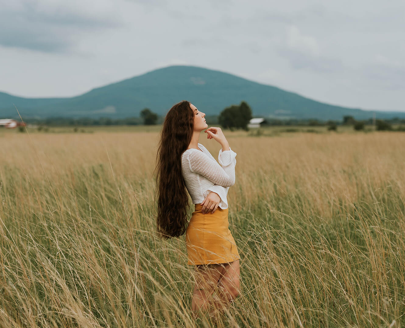 woman standing in field staring at sky thinking