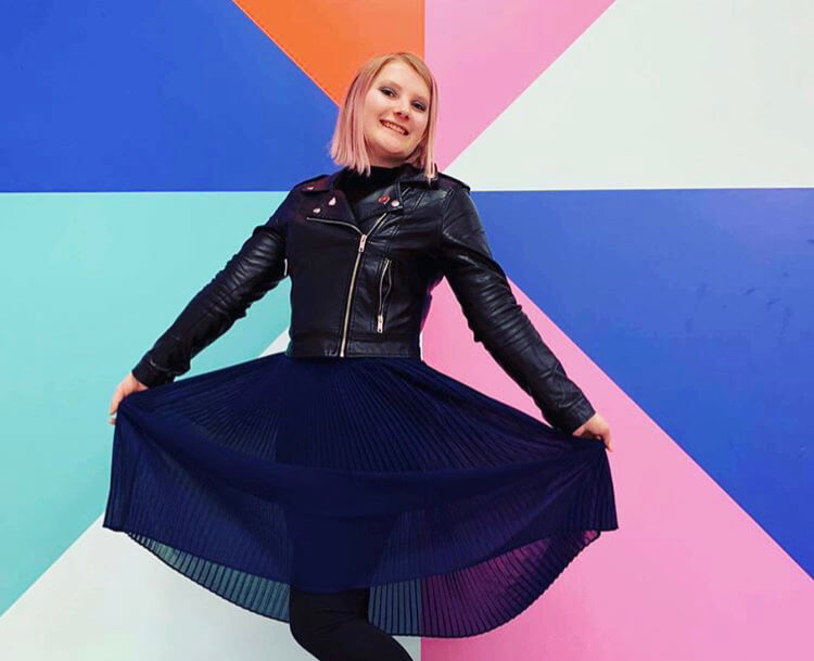 woman in skirt posing in front of colourful wall