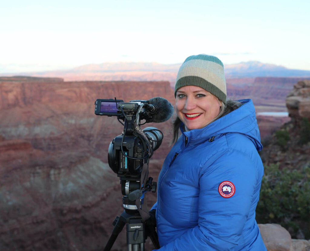 Woman stands holding a camera in Grand Canyon