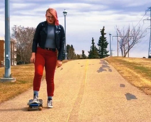 Woman rides skateboard down street
