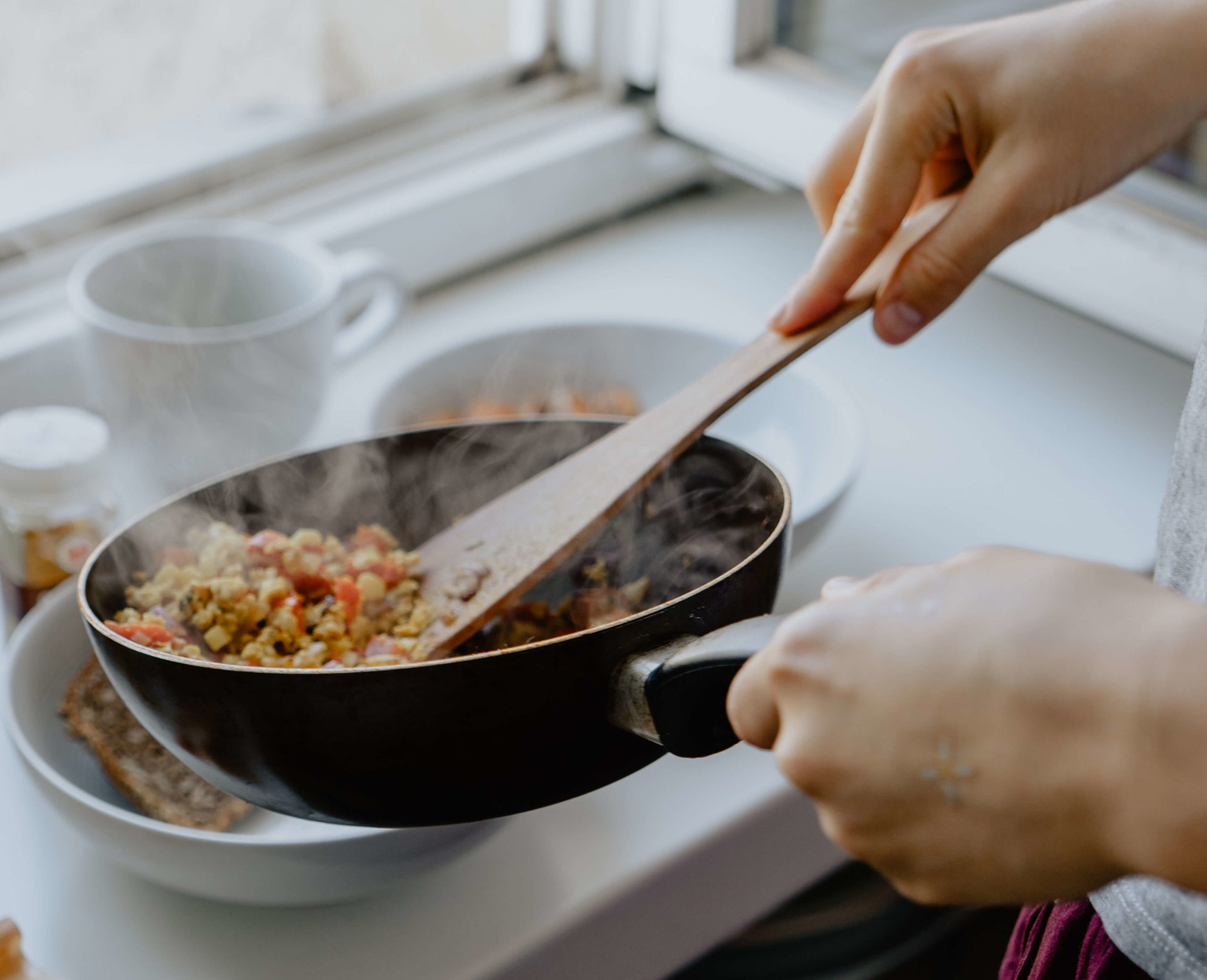 Person stirring food in frypan pan