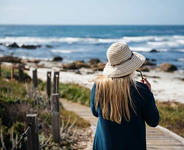 Woman stands on a beach wearing a sunhat