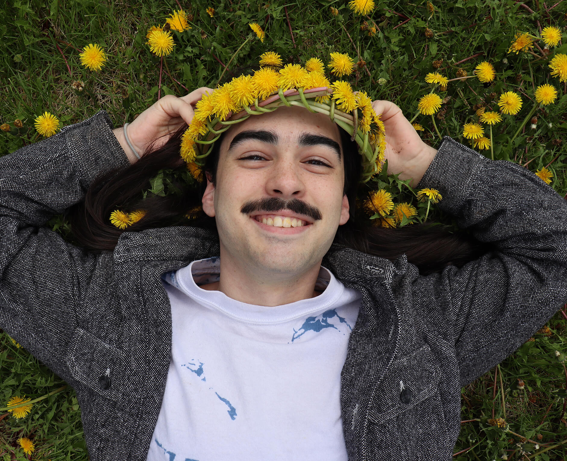 man wearing flower crown laying in grass