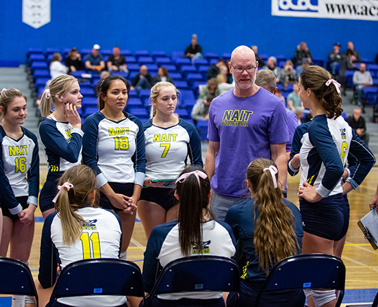 NAIT women's volleyball team and coach discuss play on sidelines