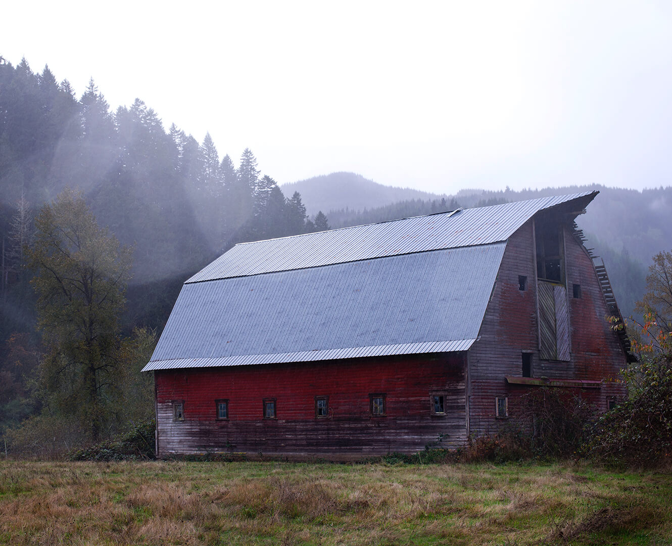 Red barn shown in a misty field