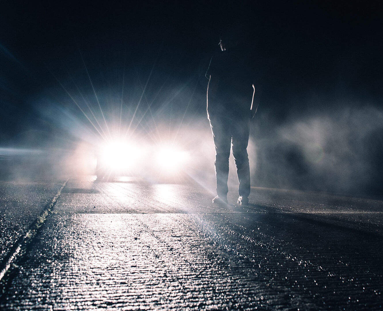 Man stands in front of truck illuminated by the headlights