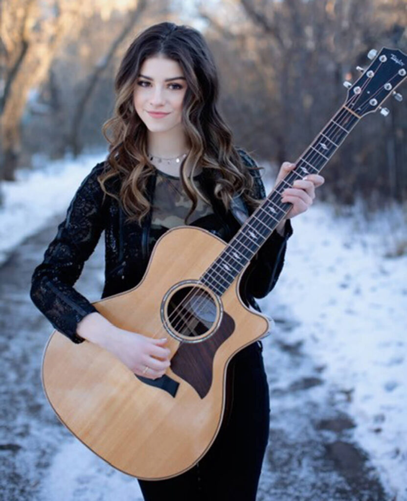 Country music star Hailey Benedict poses holding a guitar