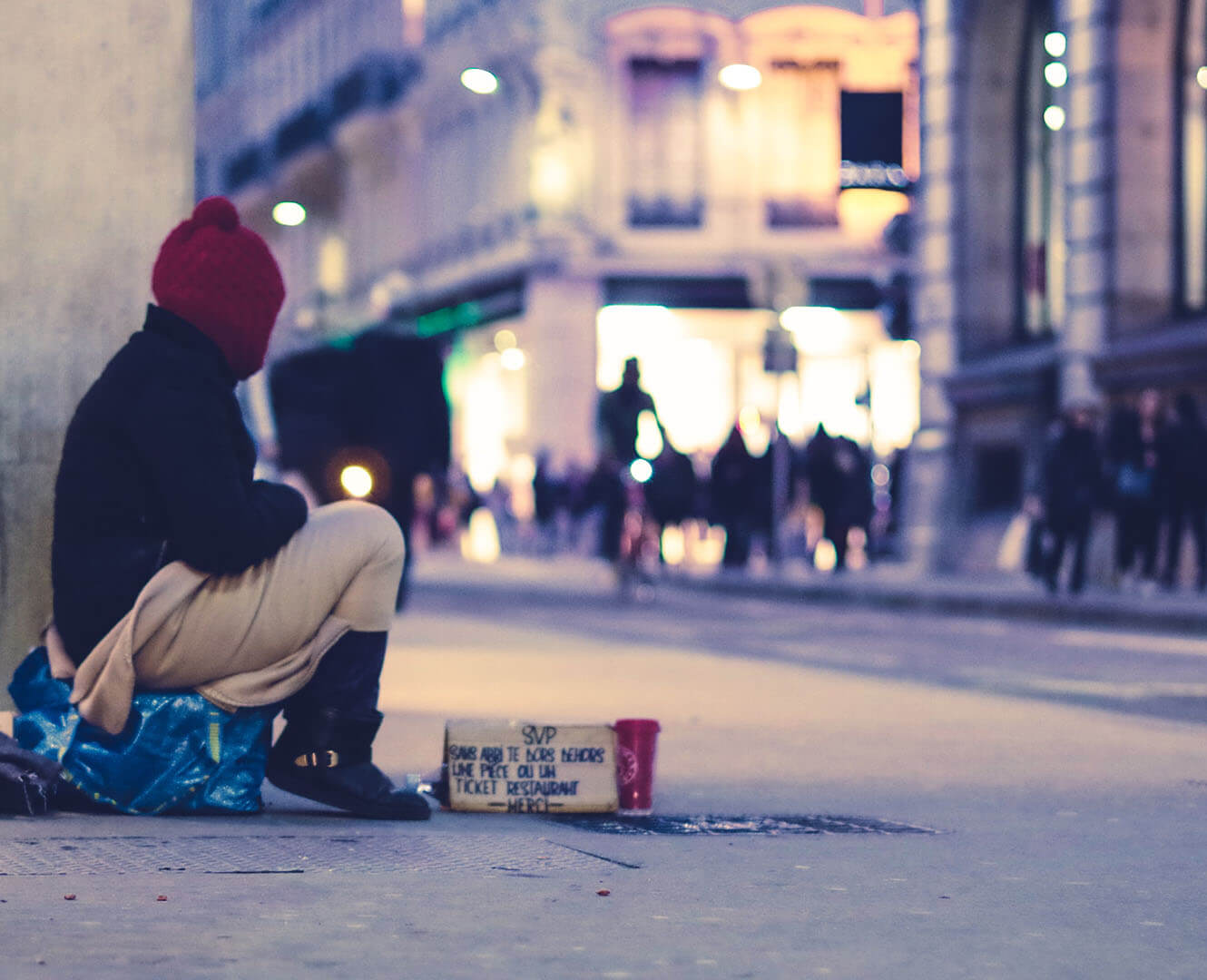 homeless person sits in busy street