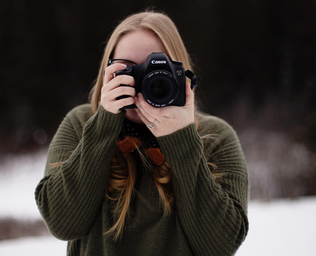 Woman stands holding camera taking photo