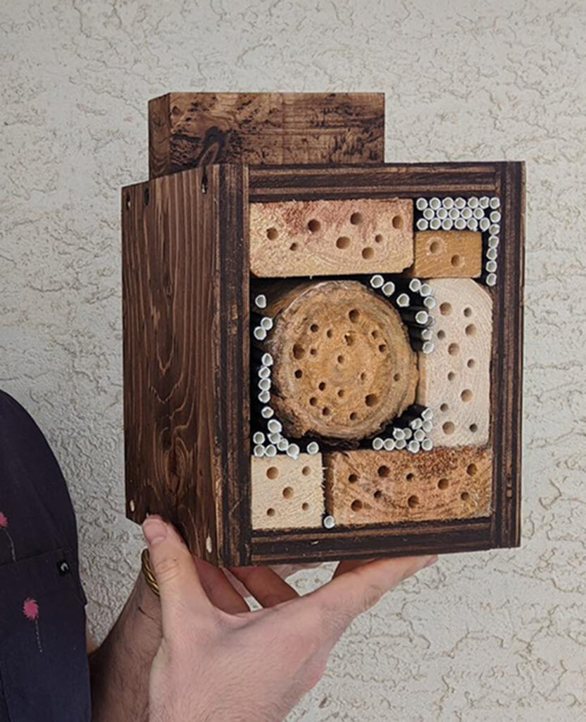 Man holds handmade bee hotel.