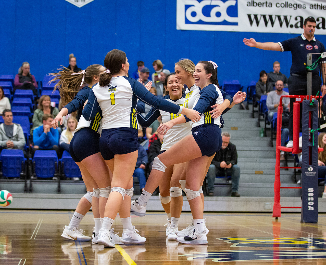 NAIT Ooks women's volley ball team in a circle celebrating