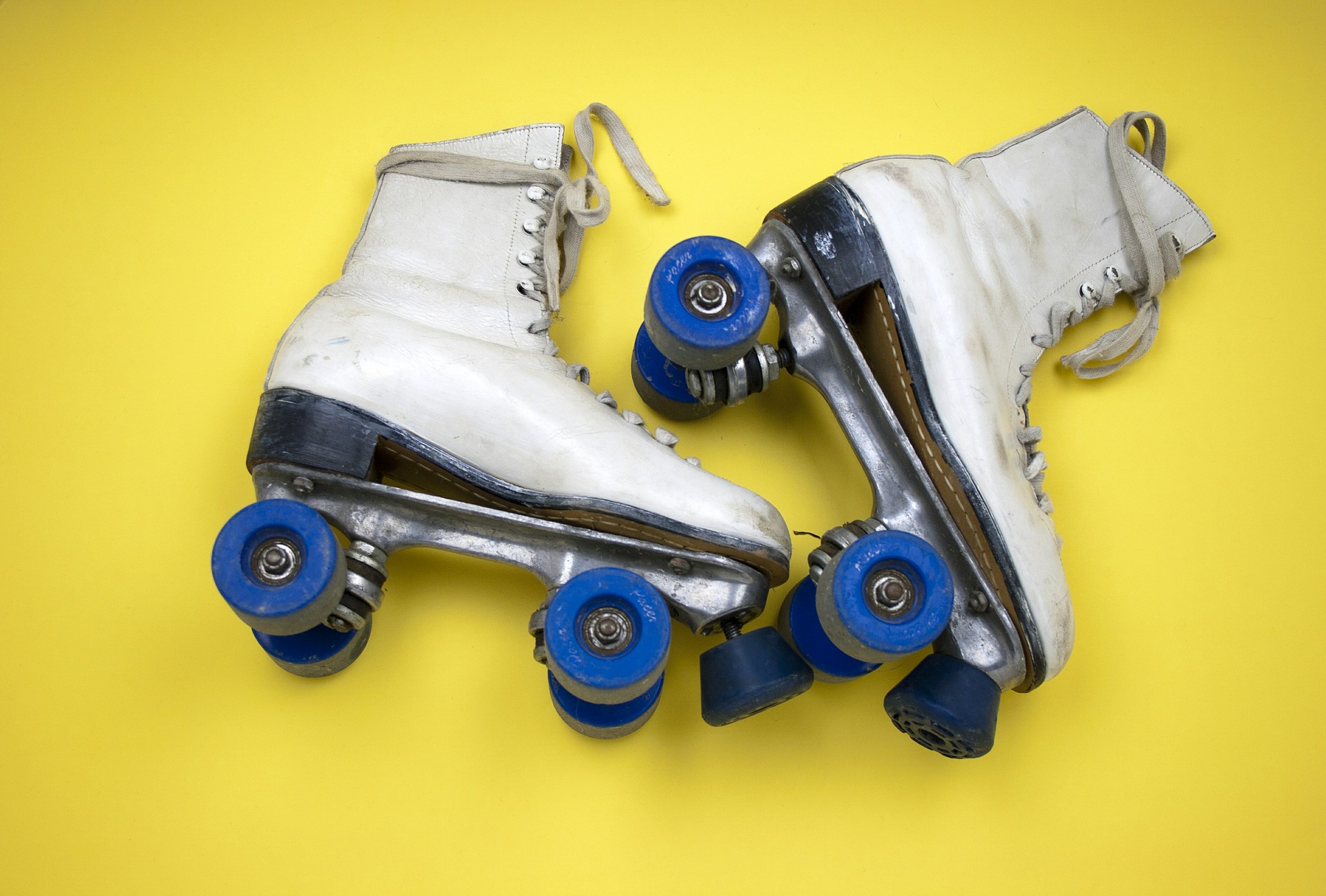 white roller skates with blue wheels on a yellow background