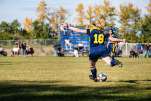 blonde woman kicking soccer balll