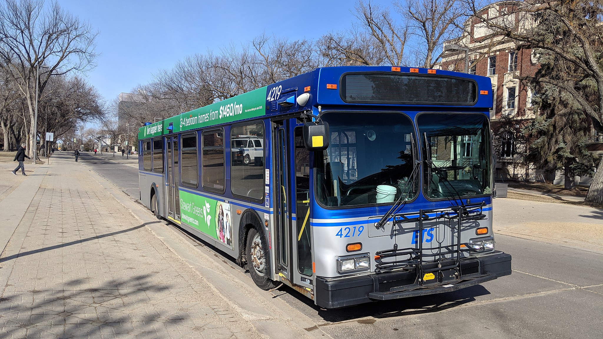an edmonton transit bus parked at a bus stop with a blue sky behind it