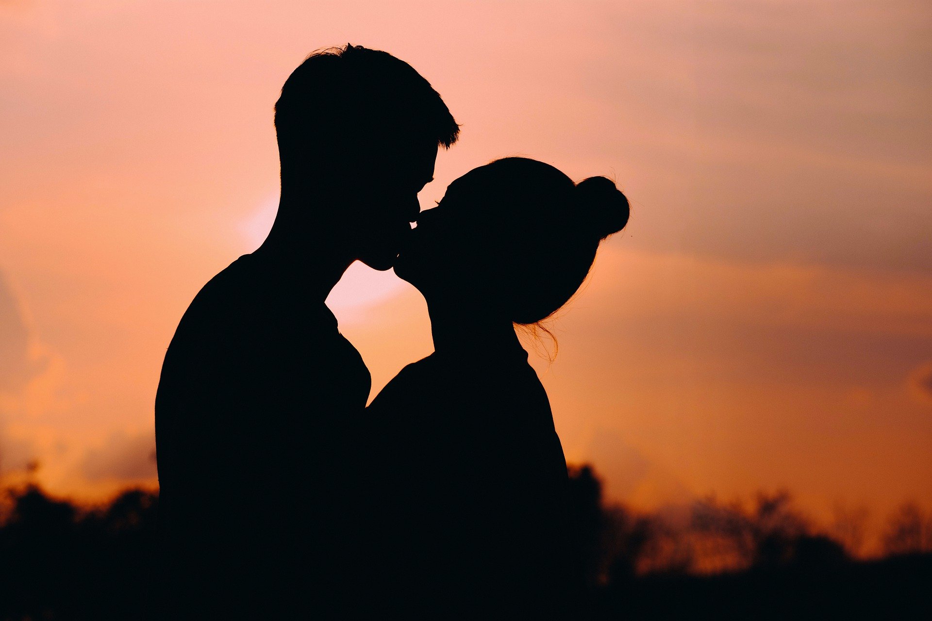 silhouette of a couple kissing in front of a sunrise