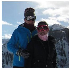 a couple in winter gear and goggles standing on a mountain