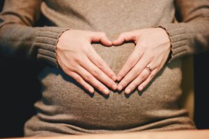 pregant woman making a heart with her hands on her belly