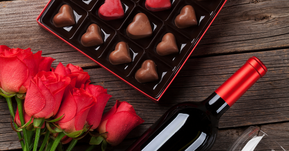 a flatlay of chocolates, roses, and a bottle of wine