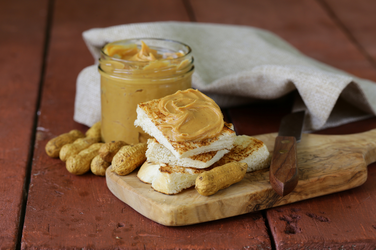 Homemade peanut butter with peanuts, toast, a knife, and cloth
