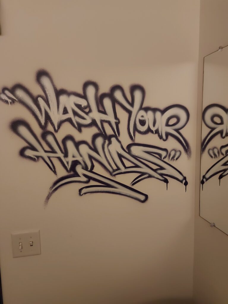 graffiti in washroom says "wash your hands"