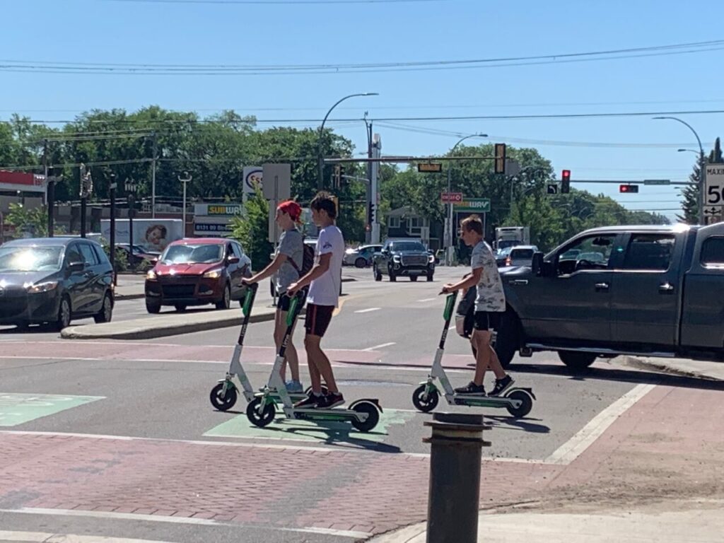 Teenagers on scooters crossing the street.