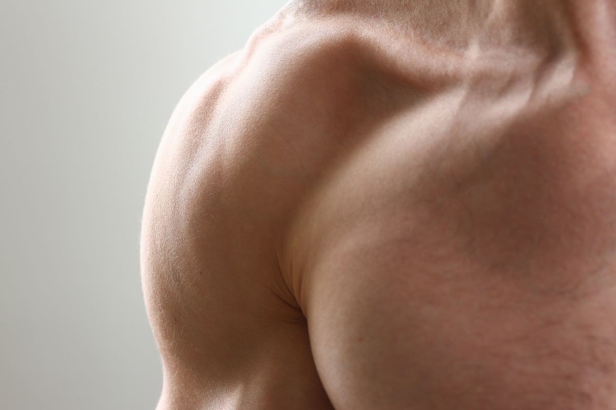 close up of a white man's shoulder muscles, you can see the muscles bulging