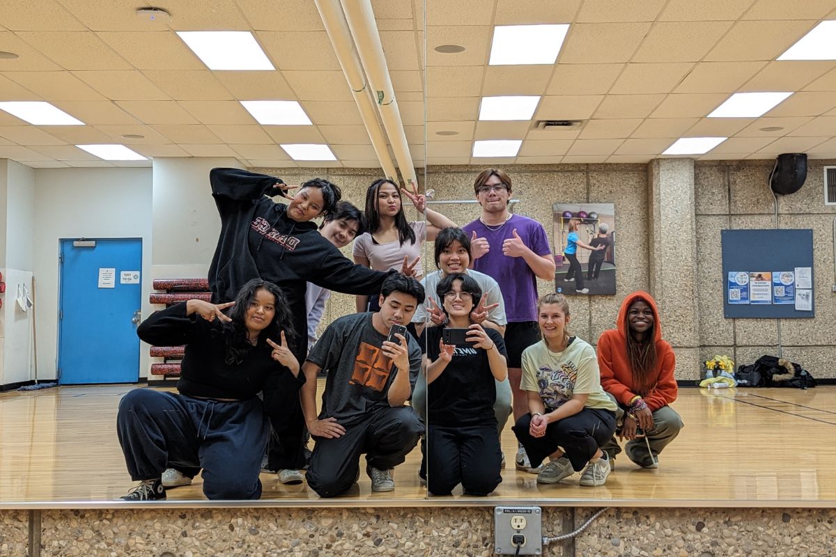 students from NAIT's hip hop dance club take a mirror selfie. they are all grouped together and smiling.