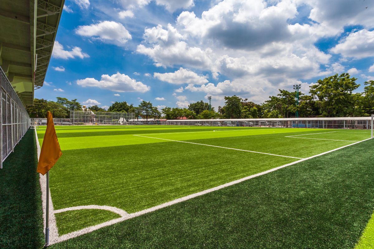 a wide shot of a grassy soccer field. the sky is blue and filled with clouds.