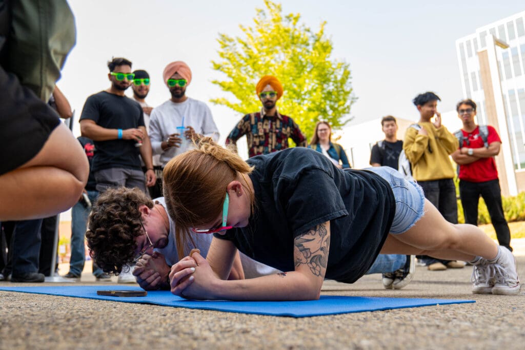 Two people are planking while a crowd watches. 