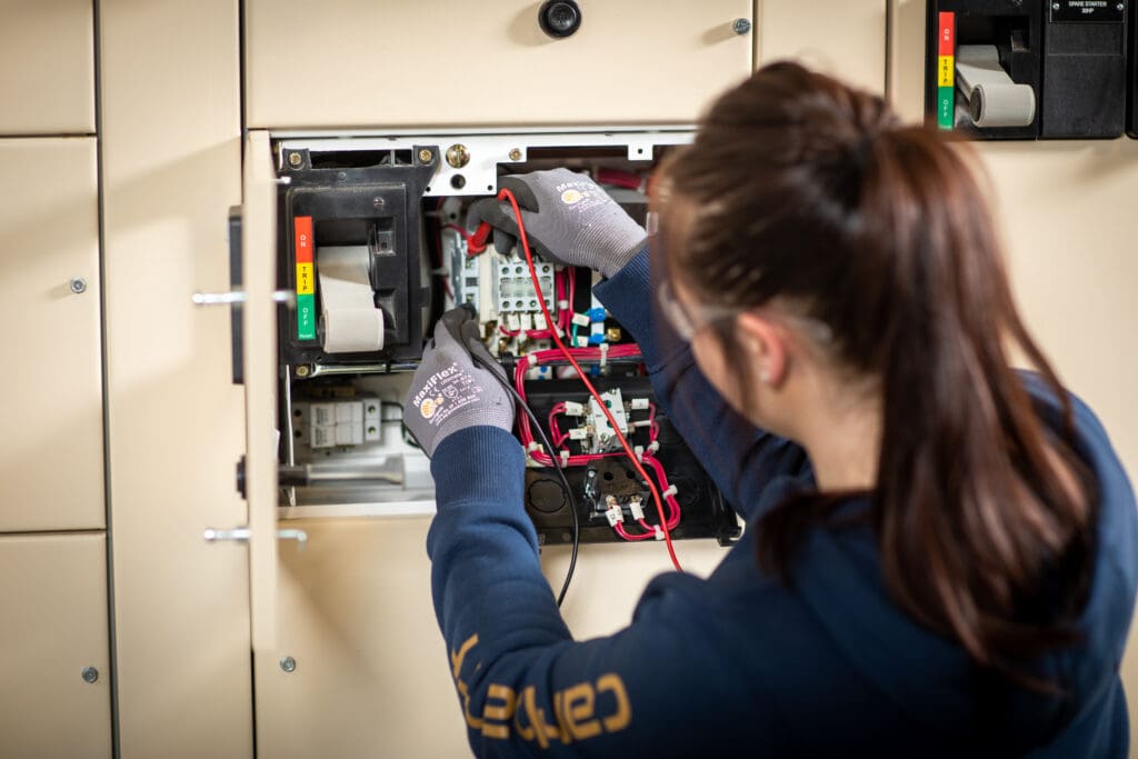 An electrician apprentice student works on an electrical panel on NAIT's main campus.