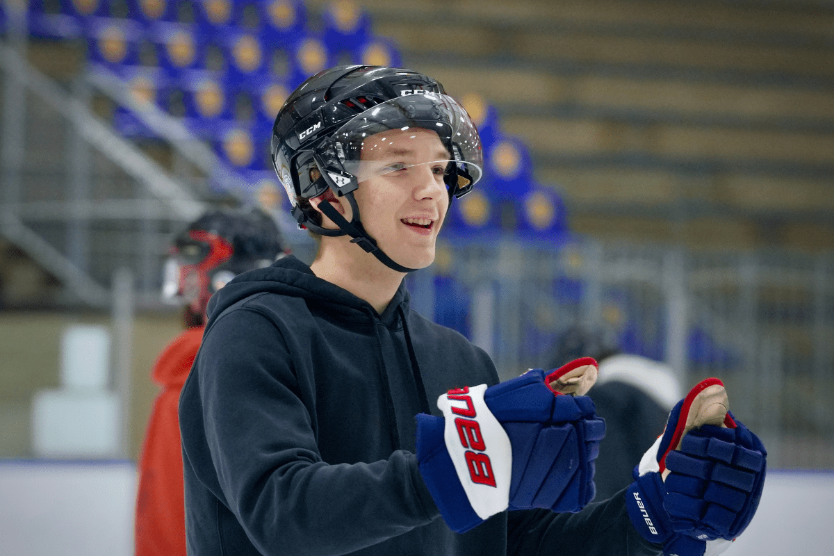 a student wearing a hockey helmet and gloves pumps his fist in celebration